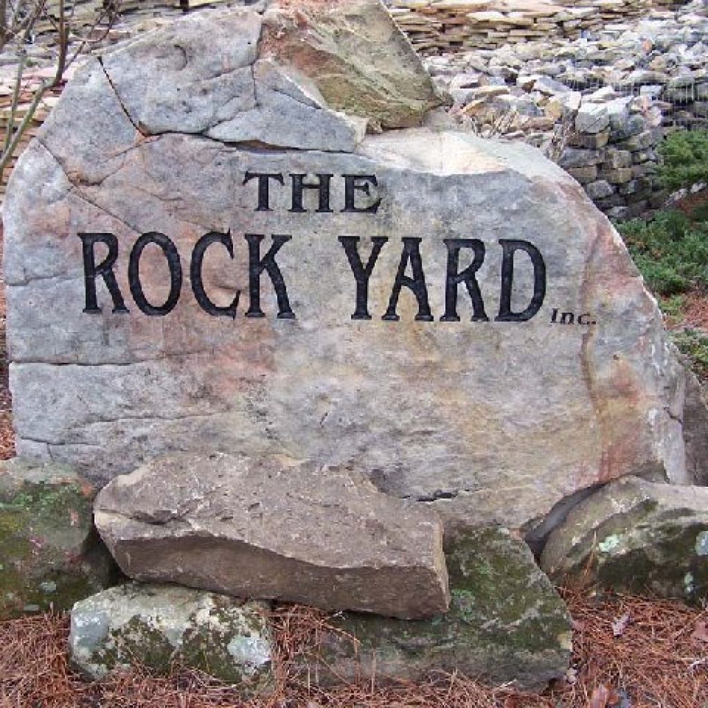 The Rock Yard Inc logo engraved on a carved boulder