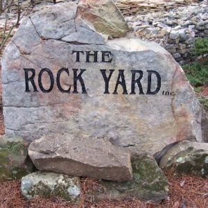 The Rock Yard Inc logo engraved on a carved boulder